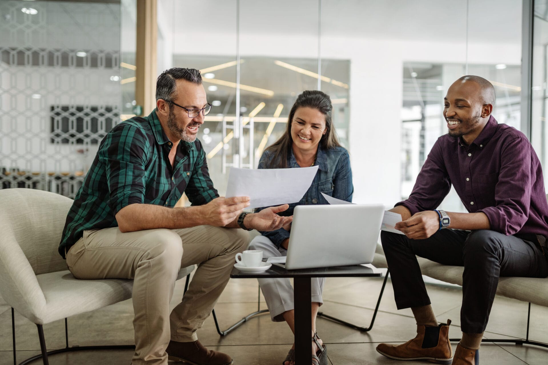Three smiling diverse business colleagues having casual sit down